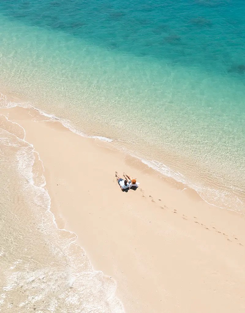 a group of people standing on top of a sandy beach